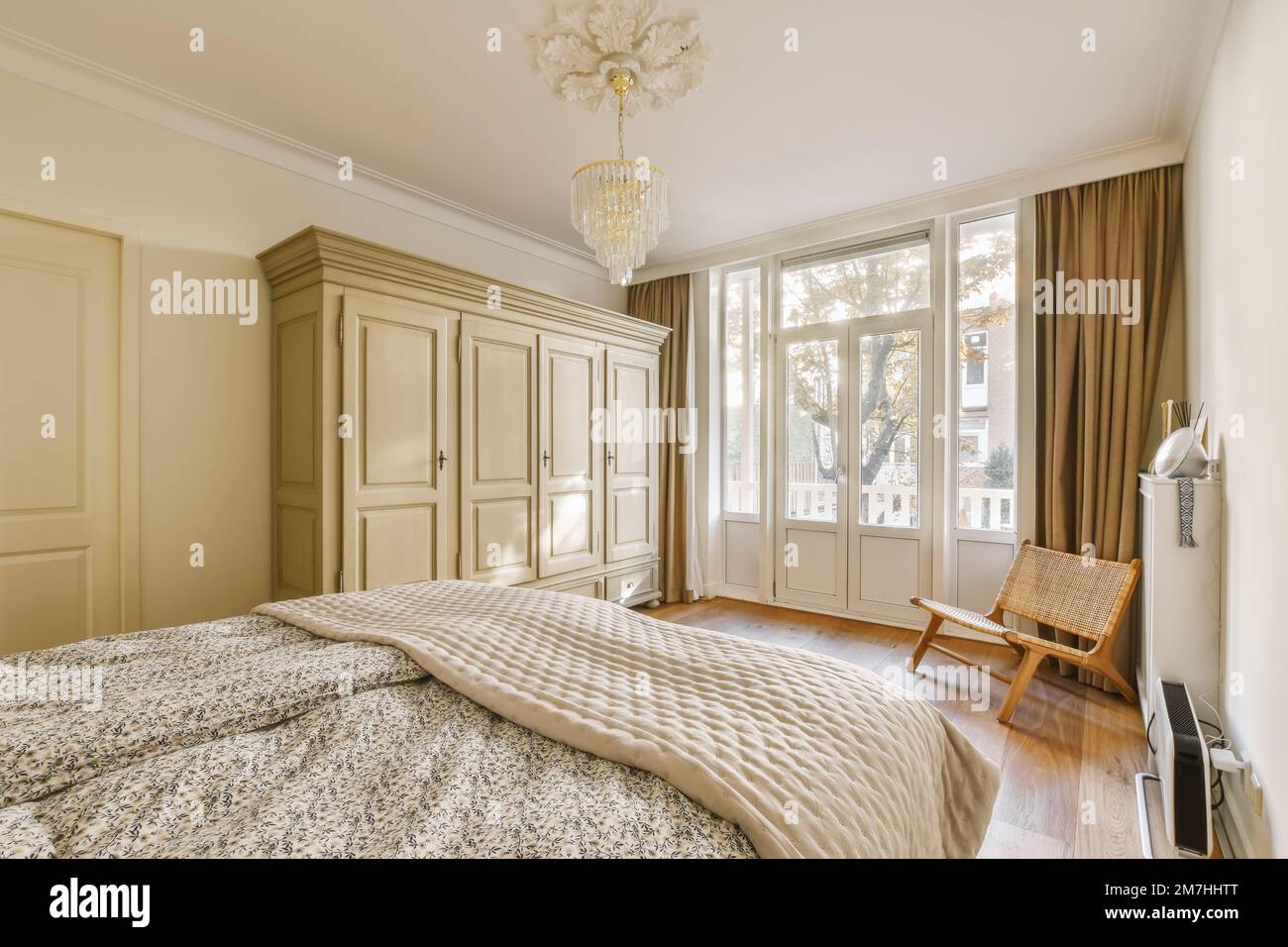Ein Schlafzimmer mit einem Bett, Stuhl und Schränken im Zimmer, wo es eine Kerze an der Wand gibt Stockfoto