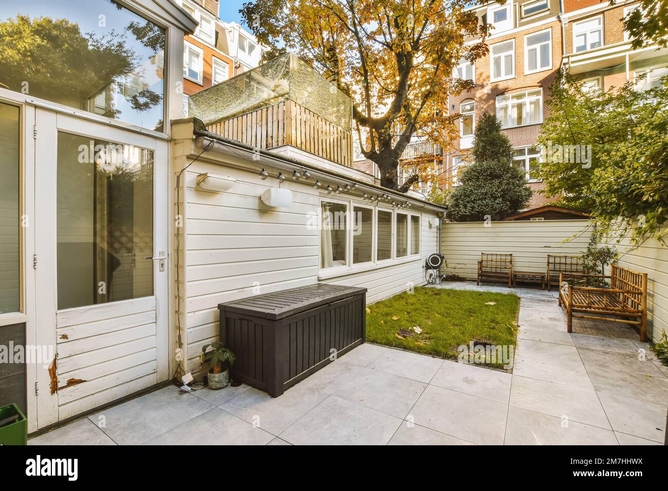 Ein Hinterhof mit einem Whirlpool im Freien in der Mitte und eine Bank auf der anderen Seite des Hauses Stockfoto