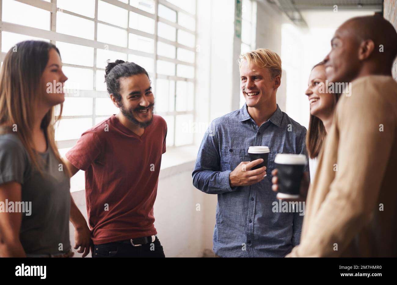 Gespräche mit Kollegen während der Arbeit. Eine vielfältige Gruppe von Freunden in einem Flur. Stockfoto