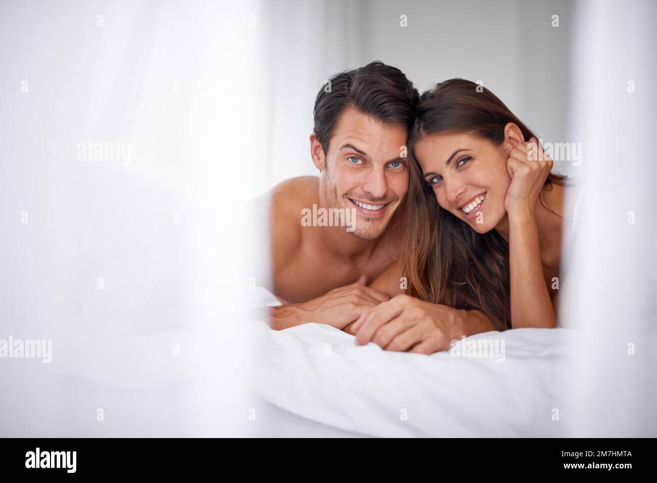 Warum in Urlaub gehen, wenn ich mit dir im Bett bleiben kann. Porträt eines wunderschönen jungen Paares, das im Bett liegt. Stockfoto