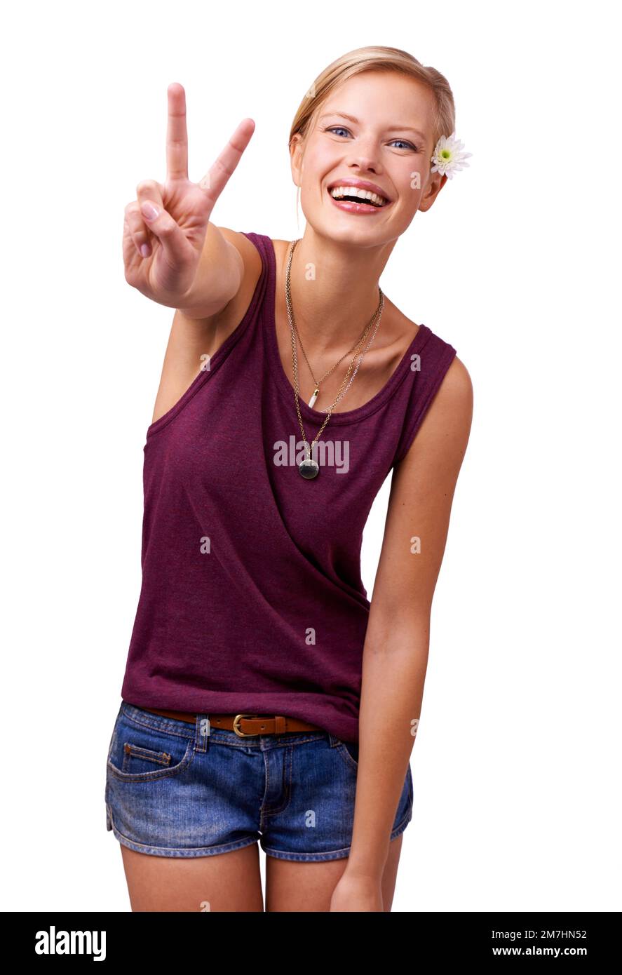 Gib dem Frieden eine Chance. Studio-Porträt einer attraktiven jungen Frau, die lacht und das Friedenszeichen auf weiß gibt. Stockfoto