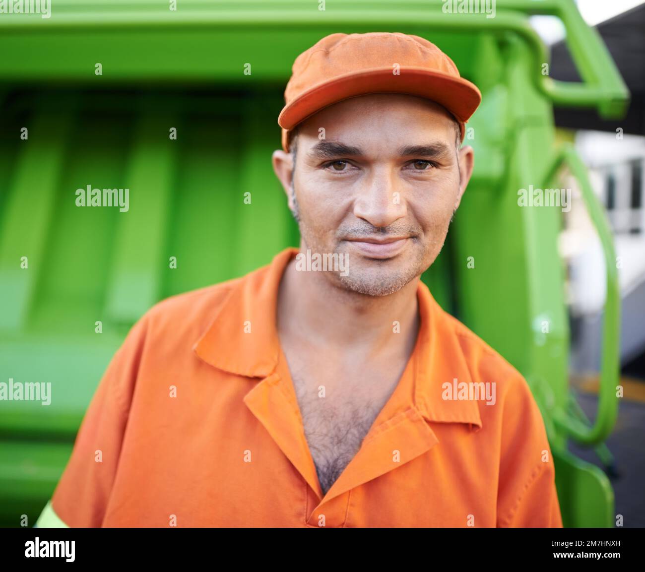 Tag der Müllabfuhr. Verkürztes Porträt eines Müllsammelarbeiters, der neben einem Müllwagen steht. Stockfoto