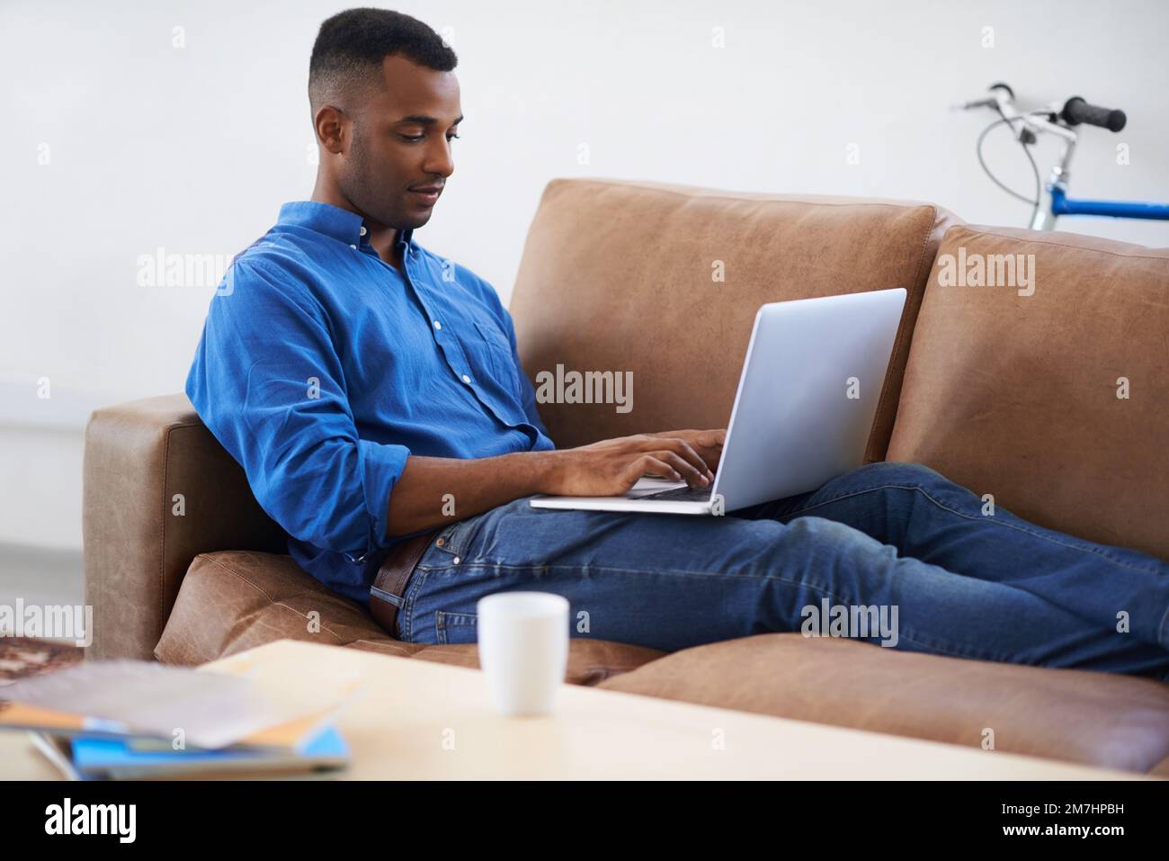 Im Internet surfen. Eine hübsche junge Frau, die auf einem Sofa mit einem drahtlosen Gerät sitzt. Stockfoto