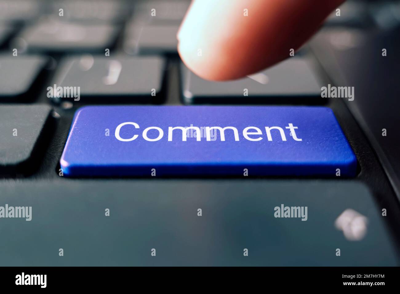 Eine farbige Schaltfläche mit dem Beschriftungskommentar auf einer schwarzen Tastatur. Stockfoto
