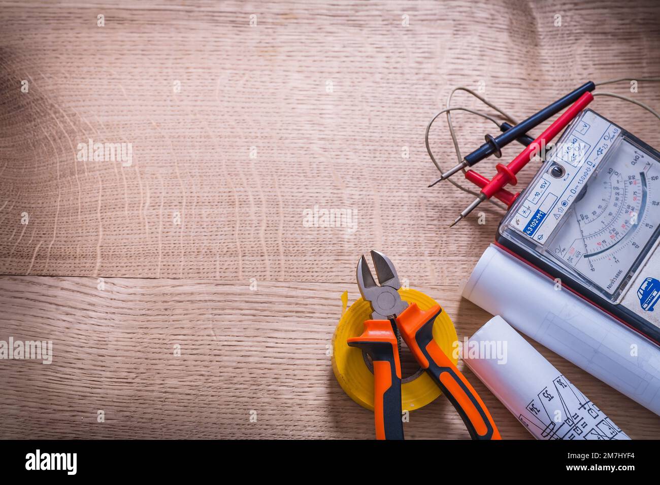 Elektrowerkzeuge Multimeter Zangen Schraubendreher Rolle Isolierband Bauplan organisierter Kopierraum auf Holzplatte Stockfoto