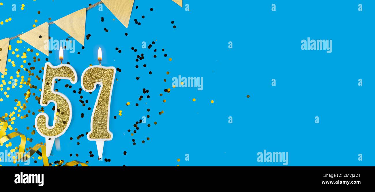 Goldene Kerze Nummer 57. Geburtstagskarte mit der Aufschrift 57 auf blauem Hintergrund. Jubiläumsfeier. Banner. Stockfoto