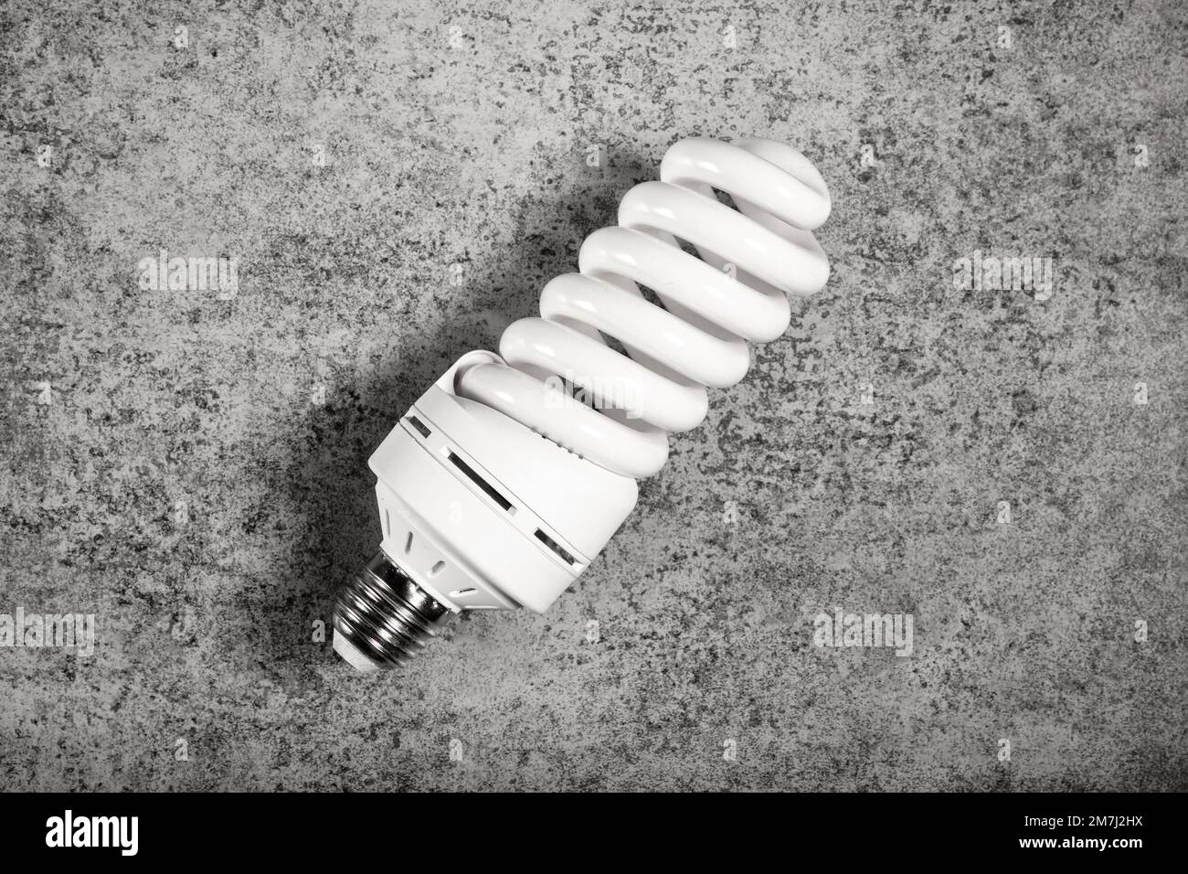 Leuchtspiralförmige Leuchte mit Sockel mit E27-Schraubkappe auf grauem Hintergrund Stockfoto