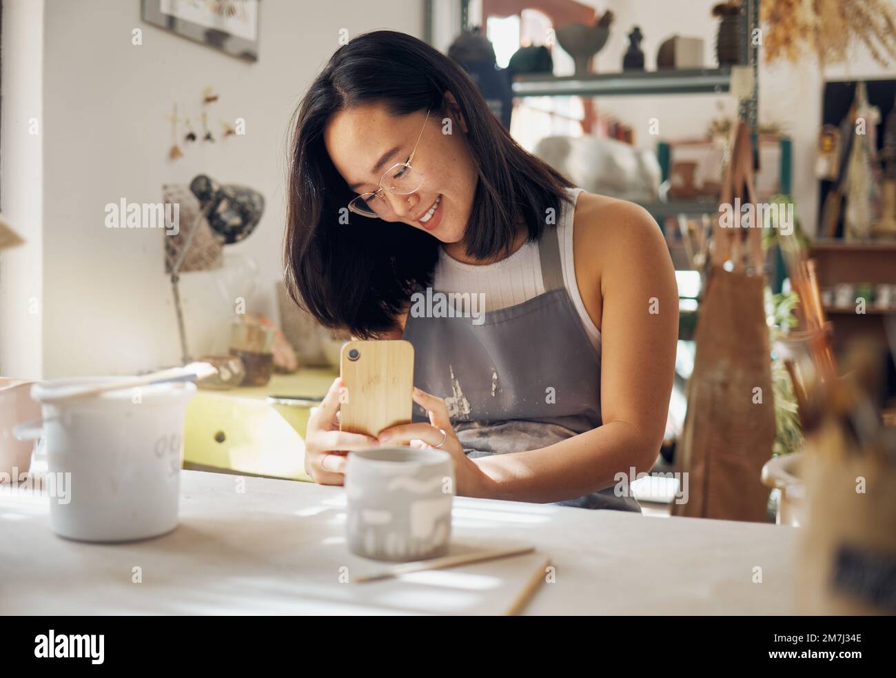 Telefonfoto, Töpferei und Frau in einem Studio für Kunstunternehmertum, Social-Media-Update und kreativen Job. Kleines Unternehmen, Kreativität und Mädchen mit einem Stockfoto