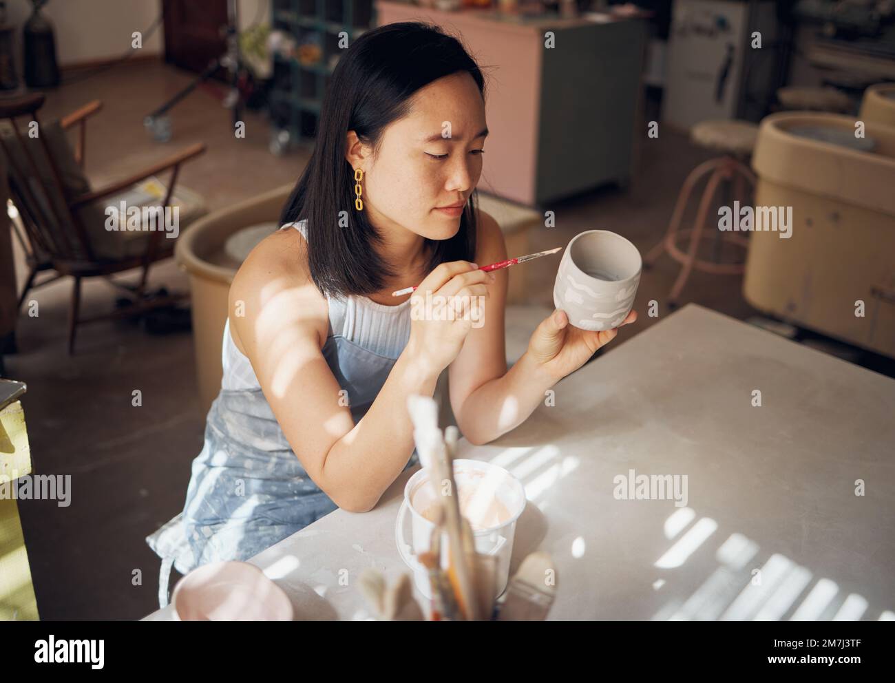 Töpferei, Kunst und Keramik mit einer asiatischen Frau in einem Designstudio oder einem kreativen Hobby als Kunsthandwerkerin. Fertigung, Muster und Künstler mit einem Stockfoto
