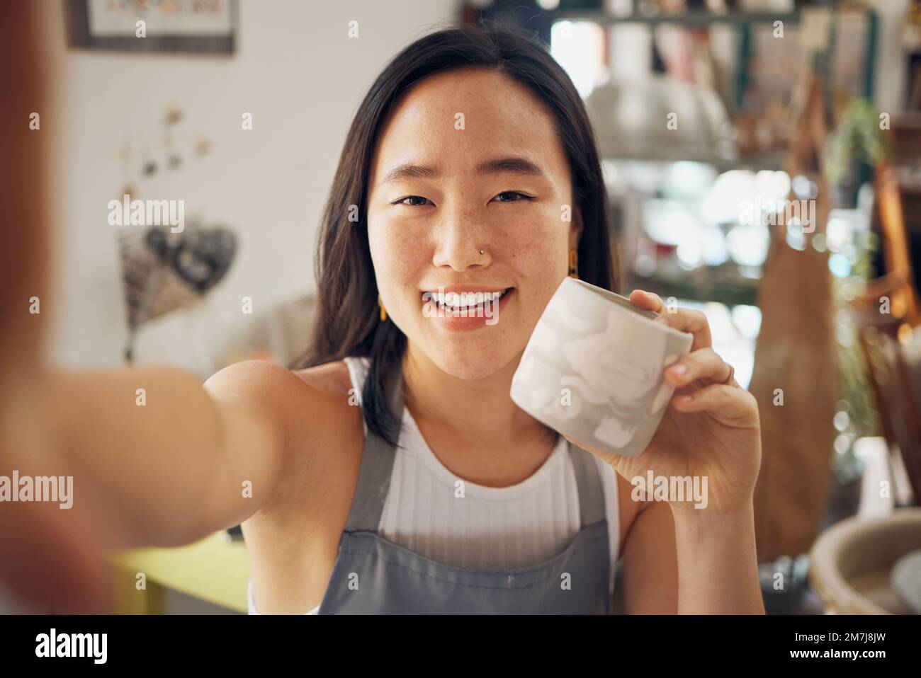 Selfie, Keramikkunst und kreative asiatische Frau lächeln im Töpferstudio oder beten für Tassen-Produktdesign, kulturelle Kreativität und künstlerische Entwicklung an Stockfoto
