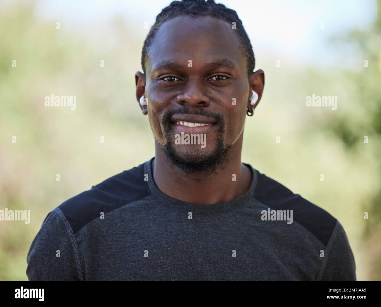 Fitness, schwarzer Mann und Porträt eines glücklichen Läufers, Kopfhörer und Training im Nigeria Park. Gesicht, Lächeln und Sportler, die Musik hören Stockfoto