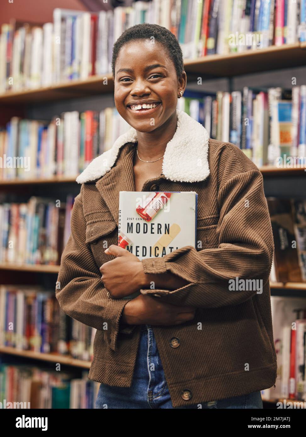 Schwarze Studentin, Porträt und Bibliothek mit Buch, Forschung oder medizinische Ausbildung mit Lächeln. Afrikanische Genz-Frau, Bücher und Regal an der Universität für Stockfoto