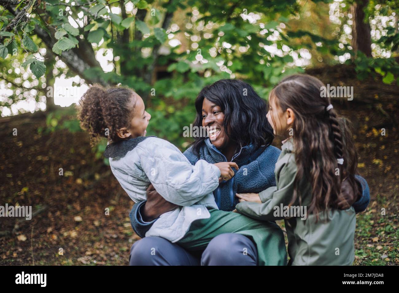 Glückliche Kinderbetreuerin, die im Park mit Mädchen spielt Stockfoto