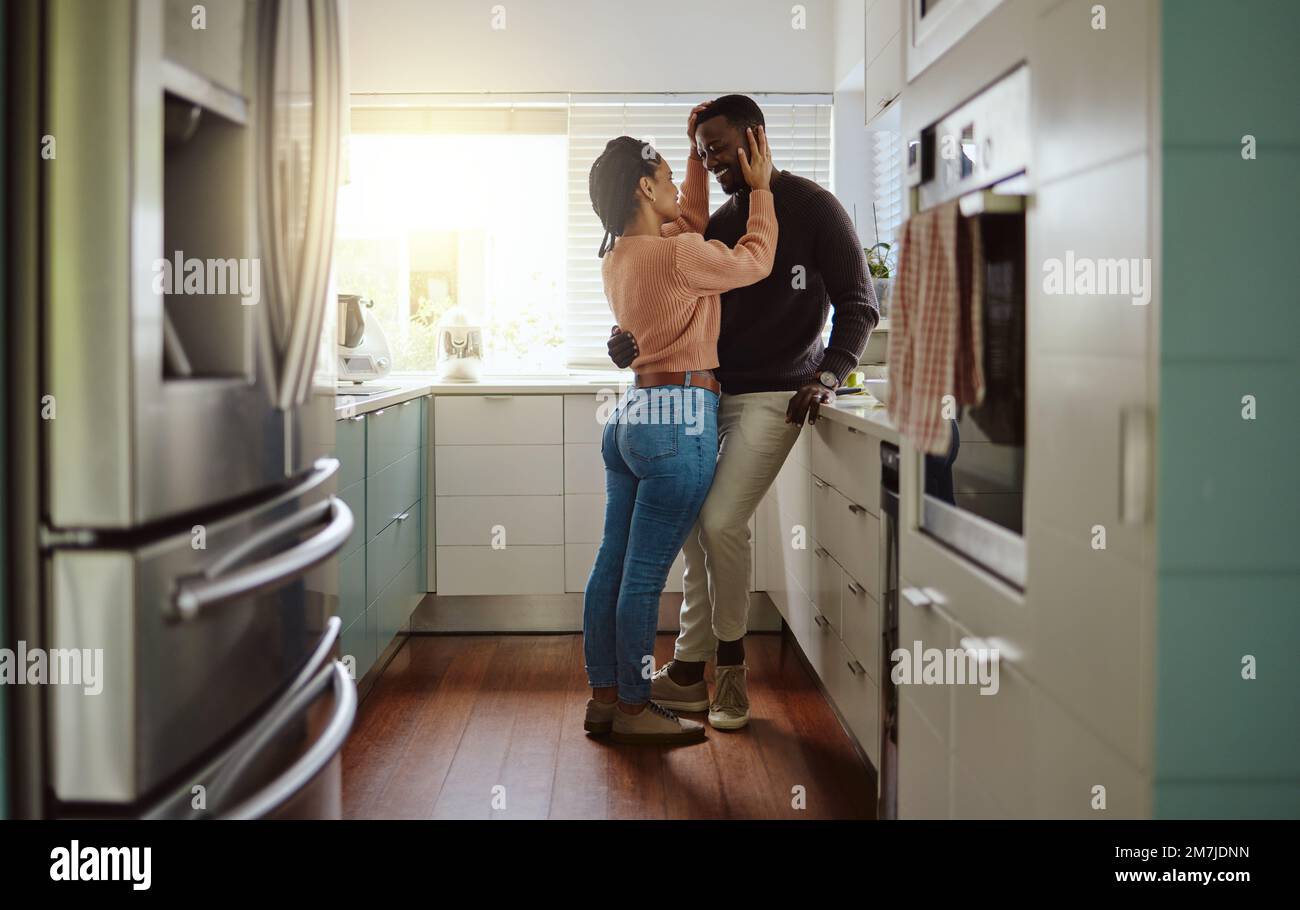 Schwarzes Paar, Liebe und Verbundenheit in der Küche zu Hause mit Fürsorge und Glück in einer Ehe mit Hingabe. Junger Mann und Frau zusammen mit einem Stockfoto