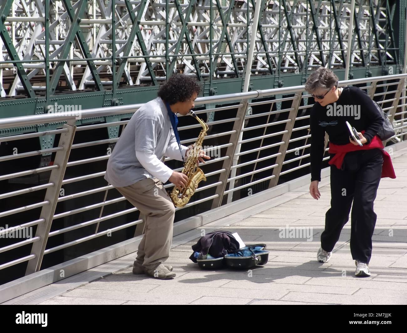 Ein Spaziergang auf der Londoner Millennium Bridge, bei dem ein Straßenmusiker Jazzmusik spielt Stockfoto