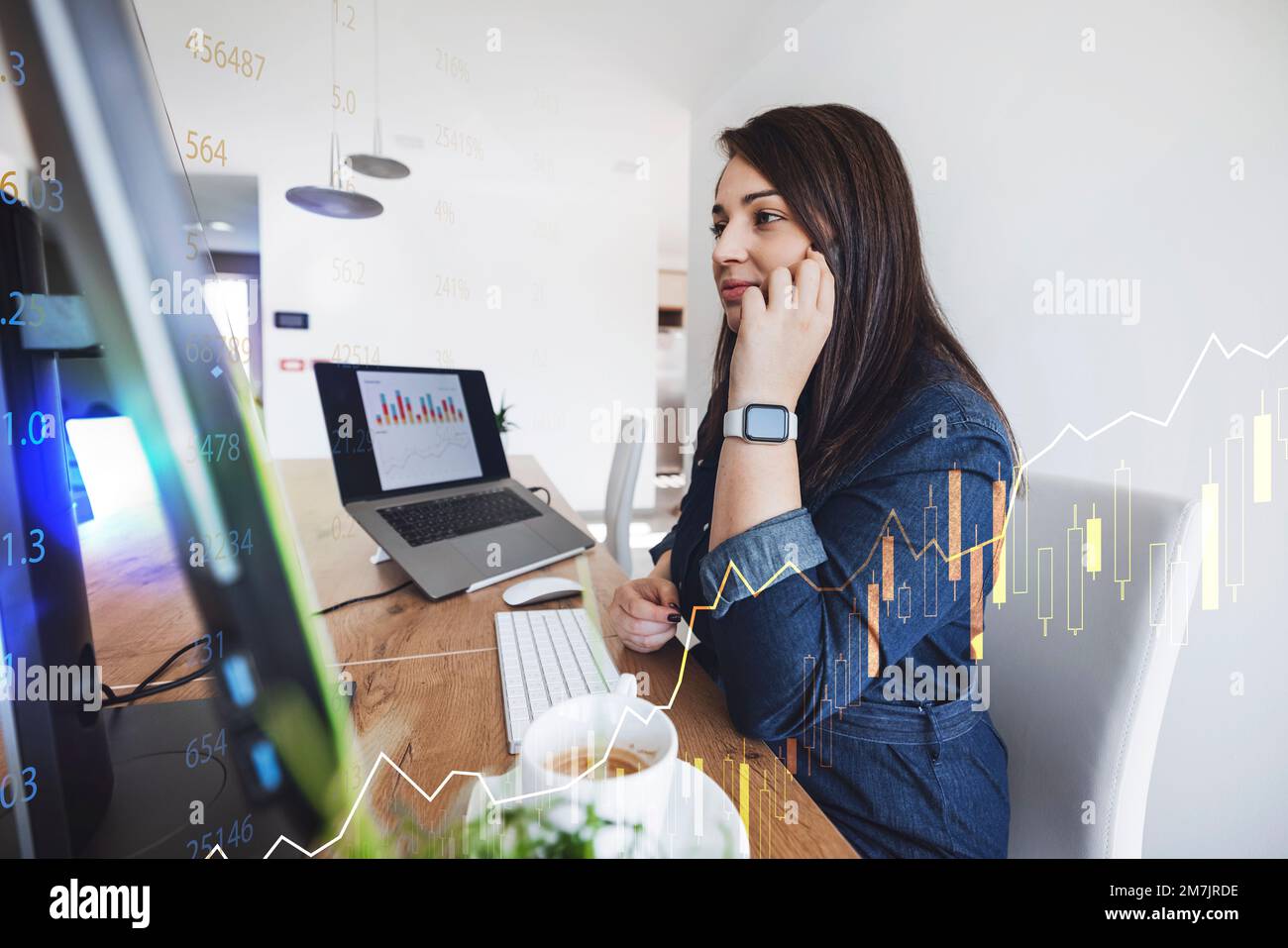 Junge weiße Frau, die in der Finanzwelt arbeitet, telefoniert am Telefon, während sie am Computer arbeitet Stockfoto