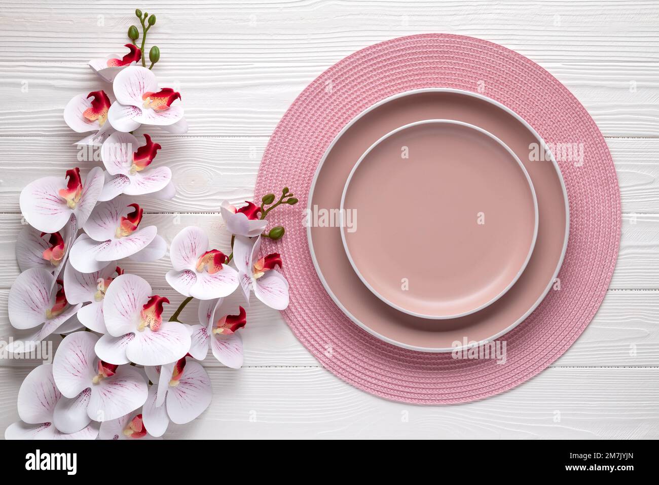 Leere Teller und runde rosa Serviette auf weißem Holztisch. Platz mit beigefarbenen Gerichten. Geschirr. Festliche Karte oder Menüvorlage mit Kopierbereich, Stockfoto
