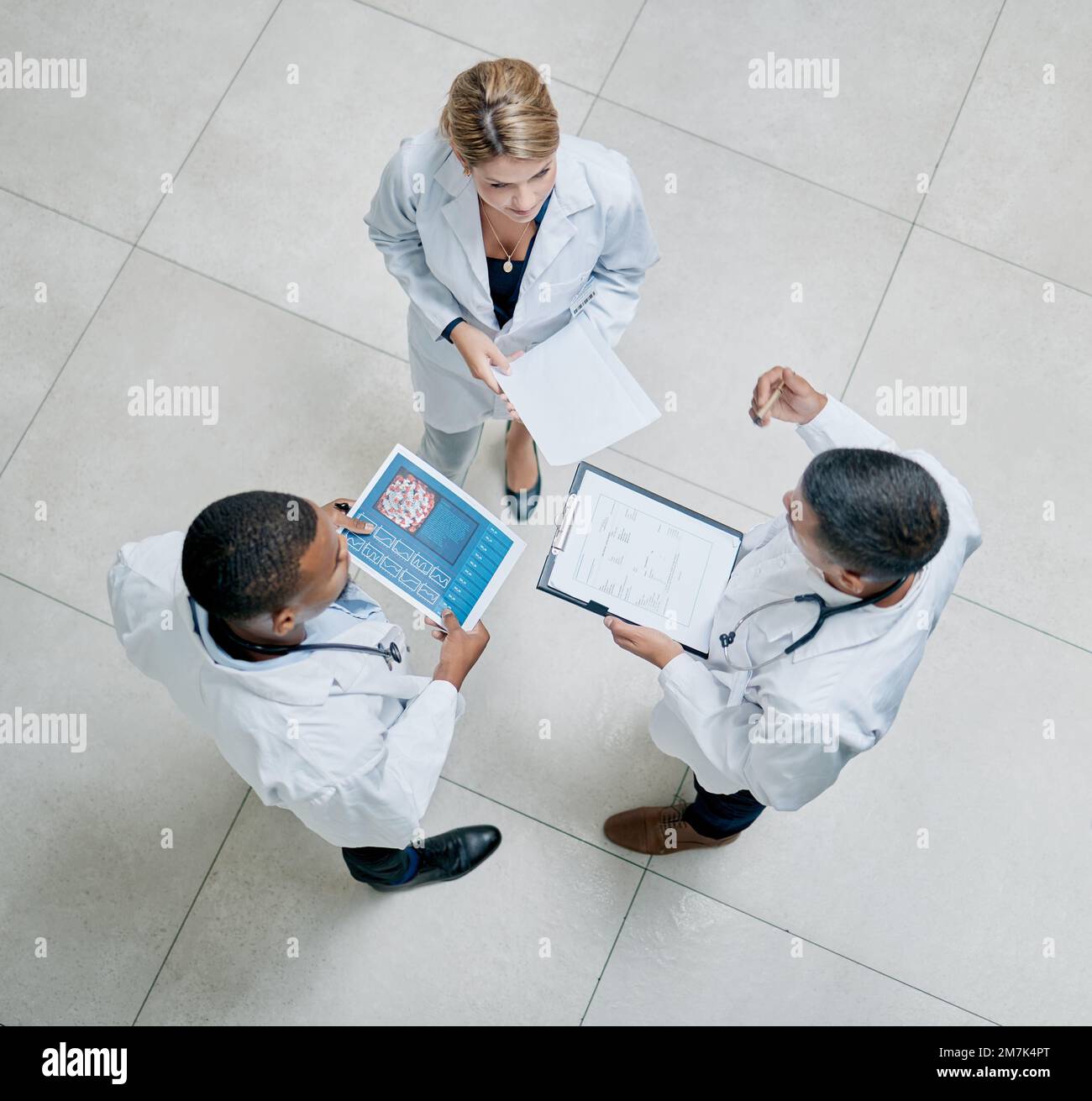 Draufsicht, Gesundheitsfürsorge und Ärzte im Gespräch, Brainstorming und Informationsaustausch. Mediziner, Männer und Frauen mit Tablet, Berichte und Stockfoto