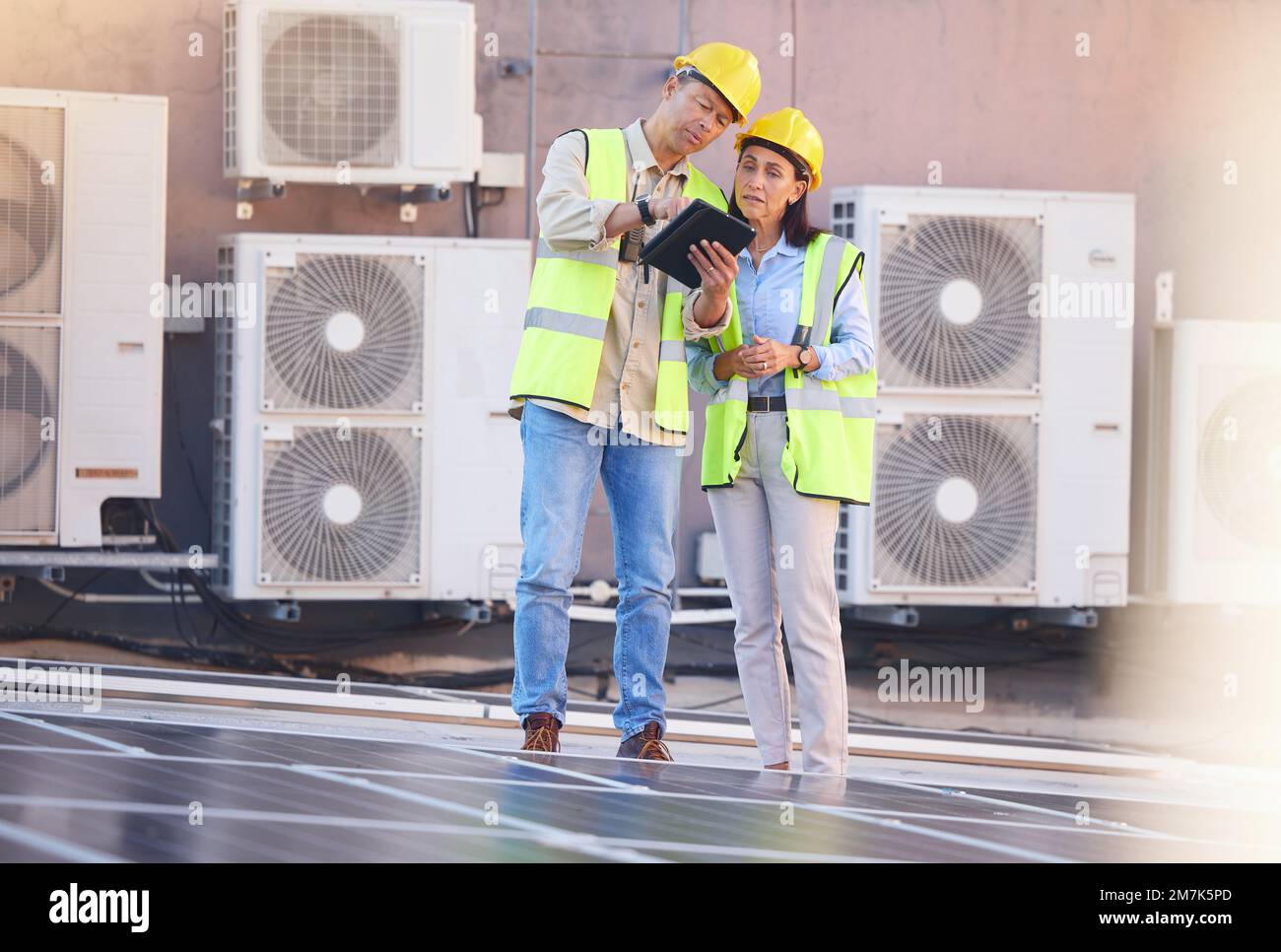 Tablet, Solarenergie oder Ingenieurteam auf dem Dach einer Stadtplanung, die über erneuerbare Energien spricht oder spricht. Solarmodule, Zusammenarbeit oder Stockfoto