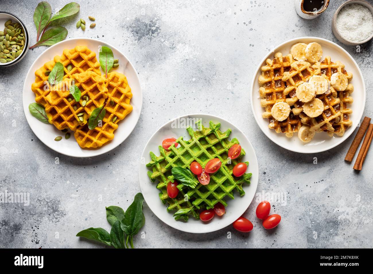 Köstliche herzhafte Waffeln mit Kürbis, Spinat und Bananen-Haferbrei auf einem grauen Tisch Stockfoto