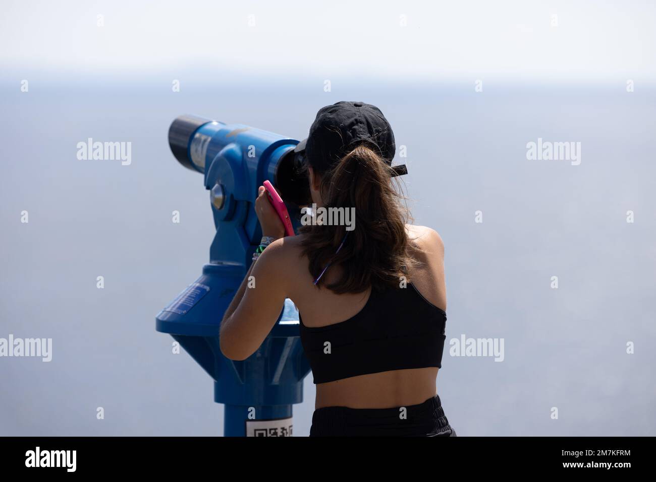 Ein braunhaariges Mädchen, das durch ein Teleskop schaut Stockfoto