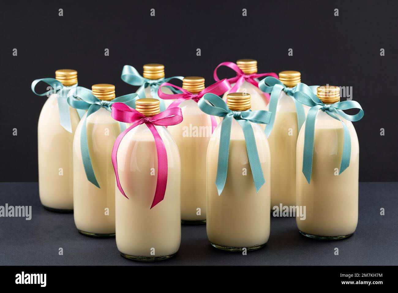 Hausgemachter Eierstockschießen in Flaschen mit blauen und rosa Schleifen auf dunklem Hintergrund Stockfoto