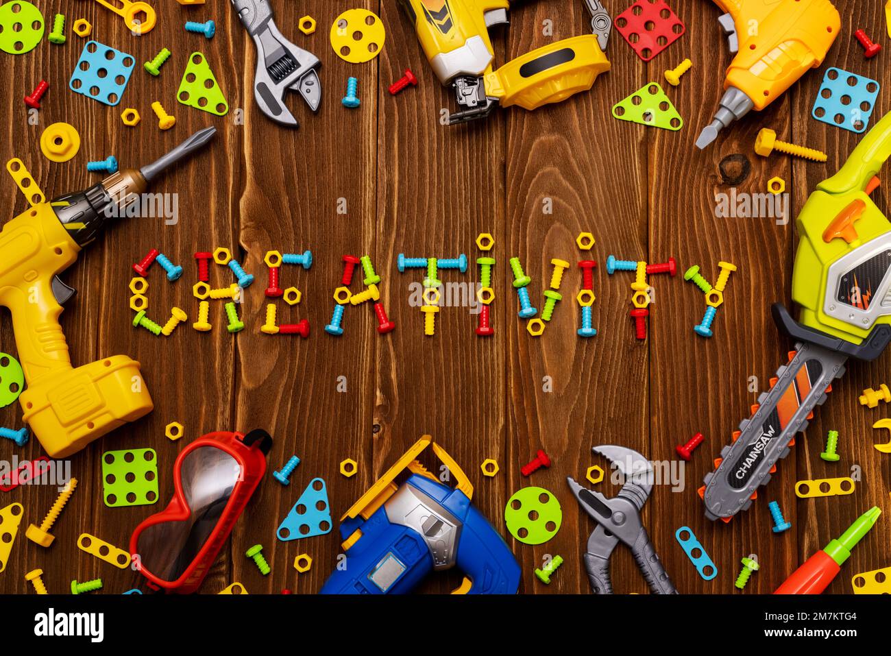 Spielzeugwerkzeuge, Bolzen und Muttern mit KREATIVEN TEXTEN auf Holzhintergrund Stockfoto