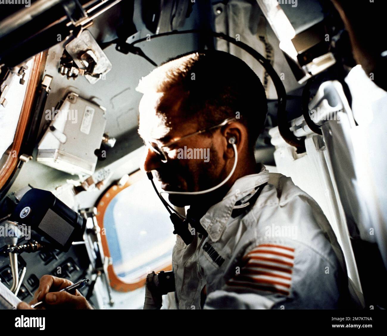 Astronaut Walter Cunningham, Pilot des Apollo 7-Mondmoduls, schreibt am neunten Tag der Apollo 7-Mission mit einem Spacestift, während er Flugaufgaben durchführt. Ein 70 mm großes Filmmagazin von Hasselbald schwebt direkt über Cunninghams rechter Hand in der Schwerelosigkeit des Raumschiffs. Land: Unbekannt Stockfoto