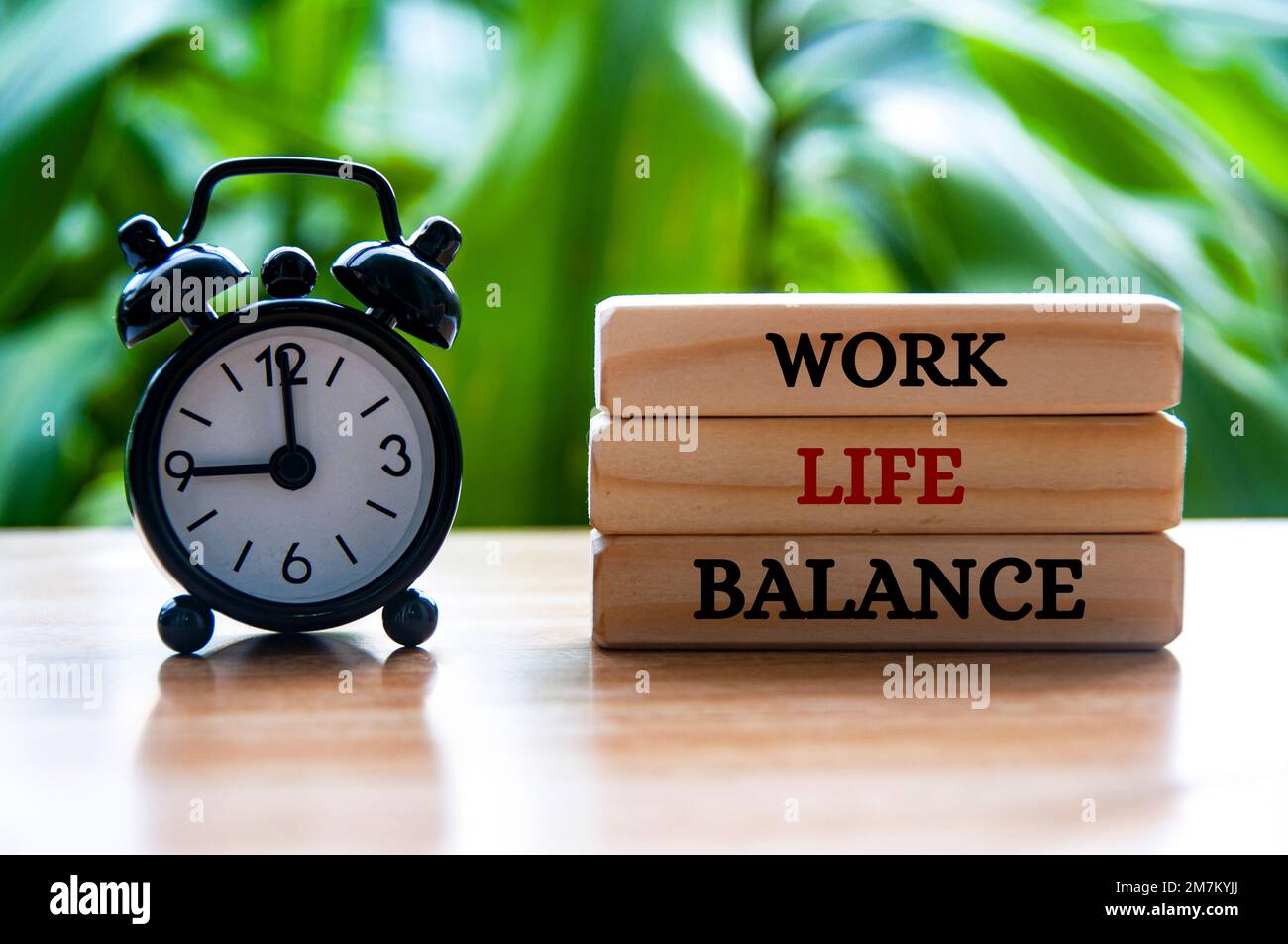 Wecker zeigt auf 9am mit Text zur Work-Life-Balance auf Holzblöcken. Stockfoto
