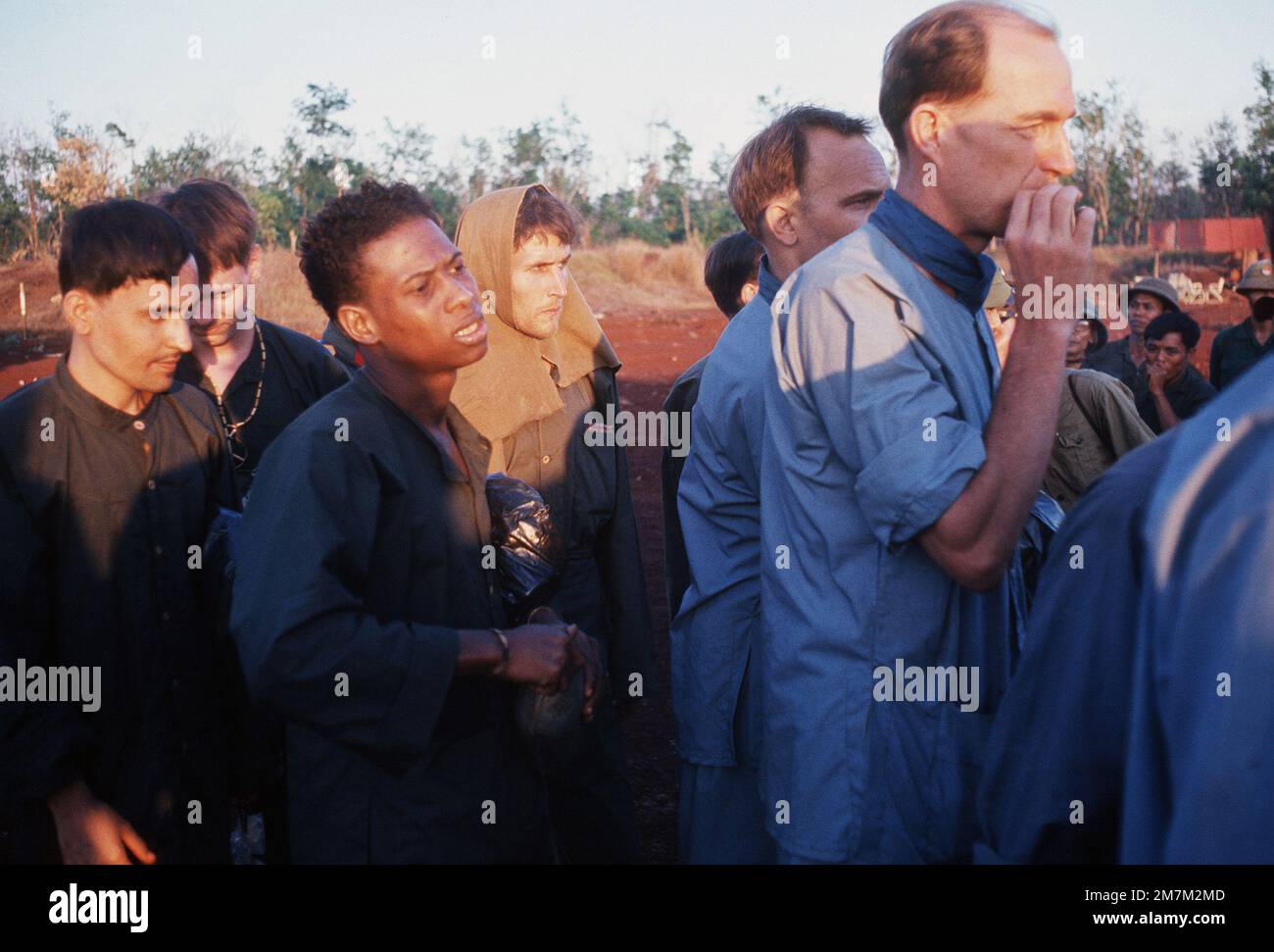 Kriegsgefangene, USA Army SGG Bobby Louis Johnson, (Schwarzer Amerikaner) wurde am 25. August 68 gefangen genommen, (in der Mitte mit Kapuze auf dem Kopf) USA Zivilist Richard George Waldhaus und (rauchende Zigarette) USA Der zivile James U. Rollins stellt sich vor ihrer Freilassung aus dem Vietcong an das amerikanische Militär auf. Sie gehören zu den achtundzwanzig amerikanischen Kriegsgefangenen, die am 12. Februar 1973 von Vietnam Cong freigelassen wurden. Subjekt Operation/Serie: HOMECOMING-Basis: Loc Ninh Country: South Vietnam Stockfoto