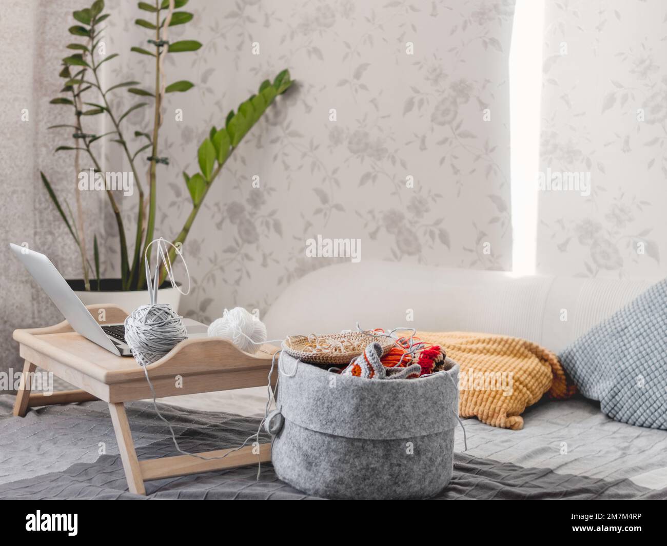 Filzkorb mit Garnen für das Stricken oder Stricken. Lernen Sie Stricken oder Häkeln in Videokursen im Internet. Gemütliches Zuhause beleuchtet mit Sonnenlicht. Stockfoto