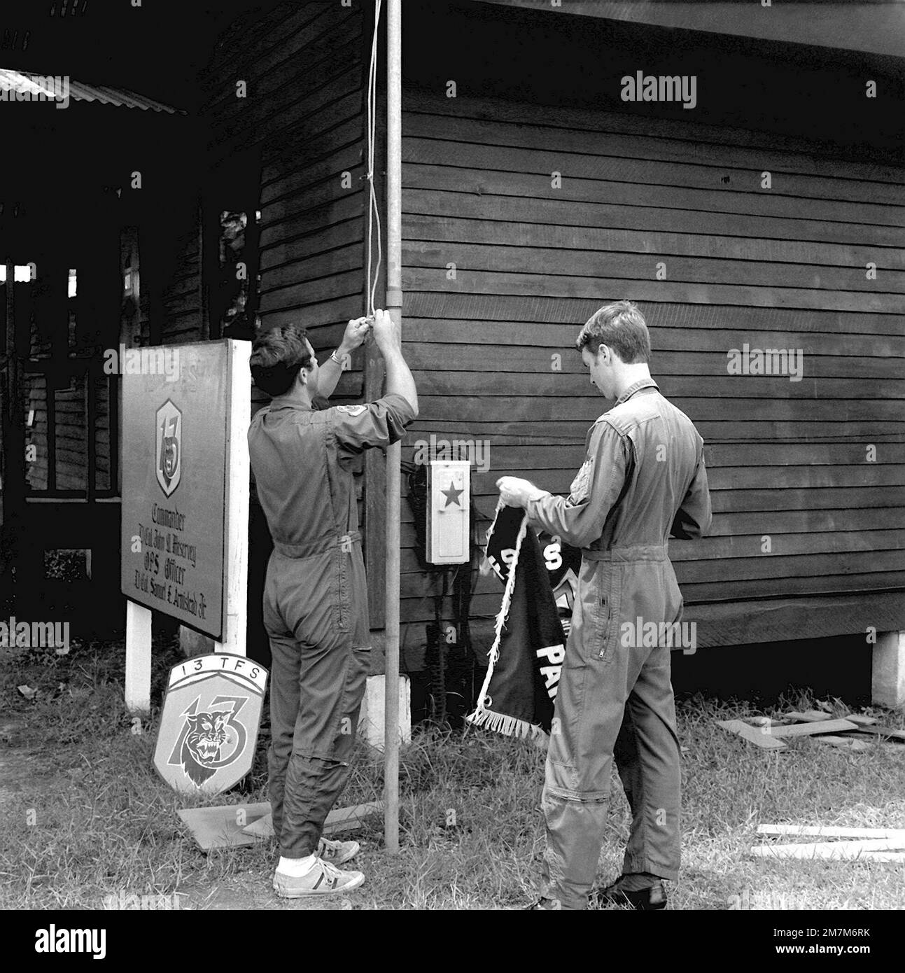 1lt Jerry Mikinis und 1LT Thomas W. Steves, links nach rechts, zum letzten Mal die Staffelflagge. Das 13. Taktische Kampfgeschwader, Panther Pack, wurde am 30. Juni 1975 deaktiviert. Basis: Udorn Royal Thai Air Force Base Country: Thailand (THA) Stockfoto