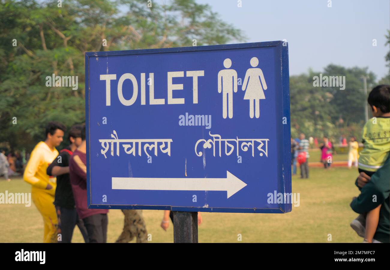 WC-Richtungstafel in drei Sprachen, Englisch, Hindi und Bengalisch, auf einem blauen Schild. Stockfoto