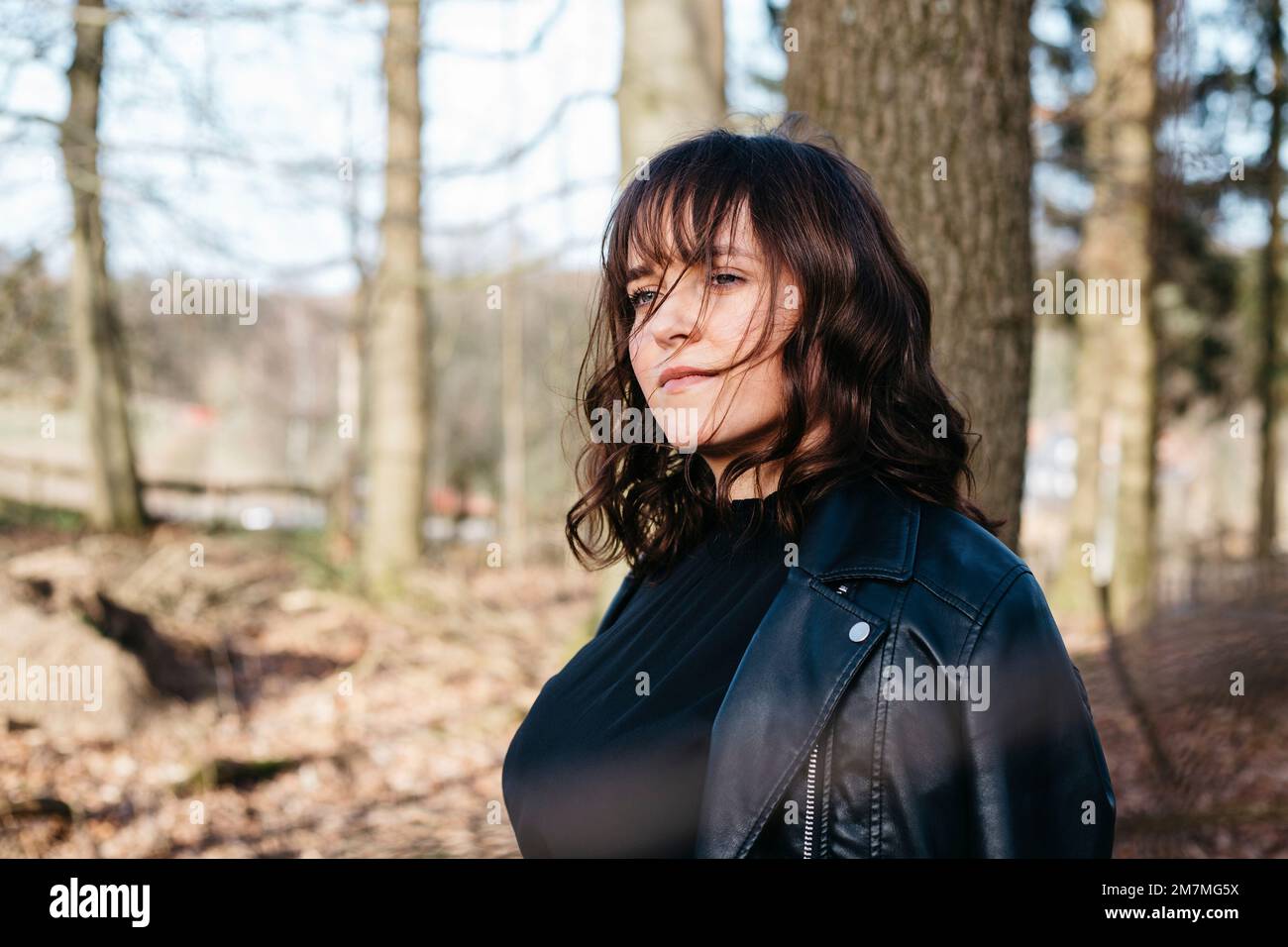 Junge Frau, die im Wald im Gedanken verloren ist Stockfoto