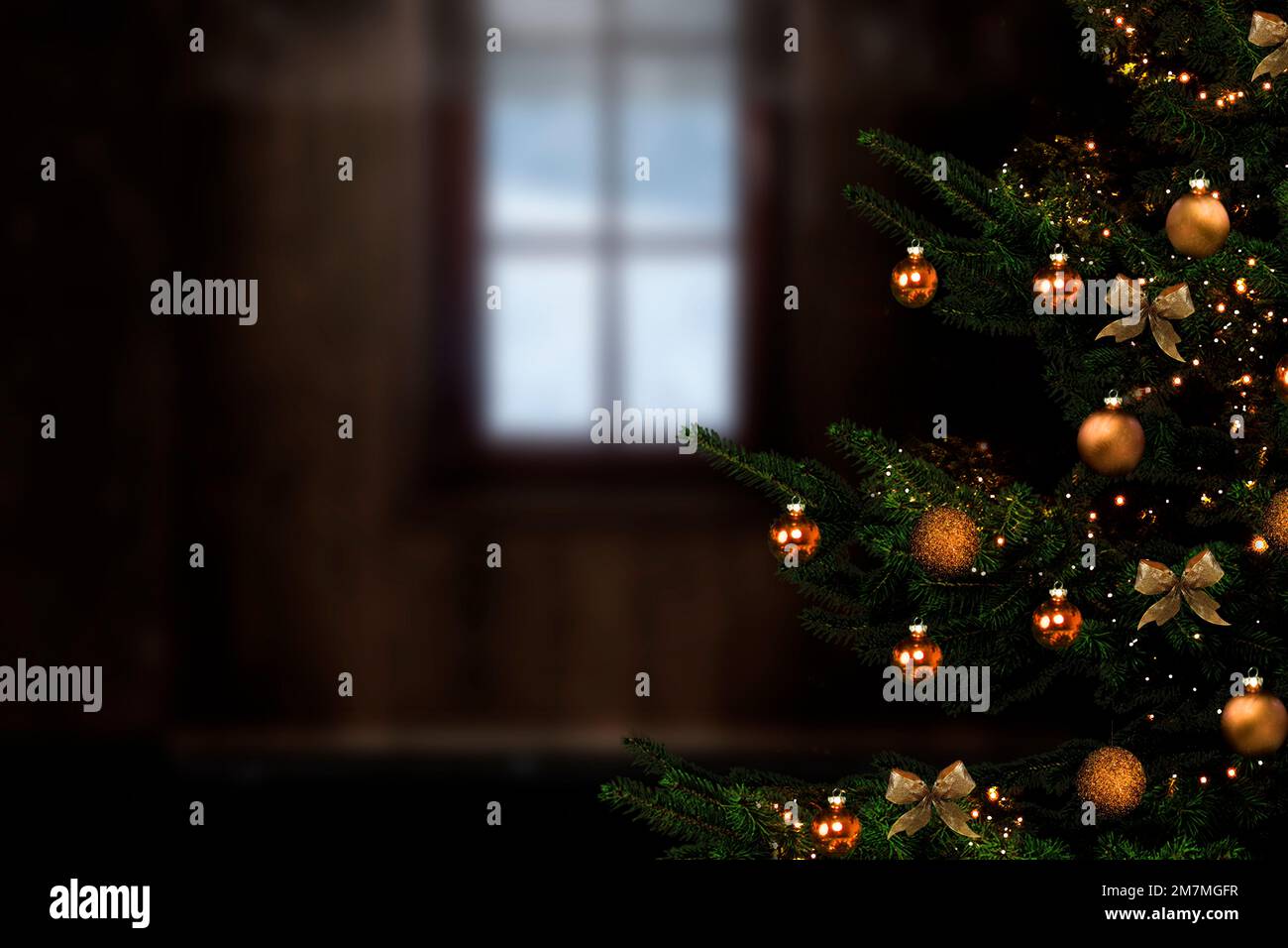 Weihnachtsbaum mit goldenen Kugeln vor verschwommenem Hintergrund mit Fenster Stockfoto