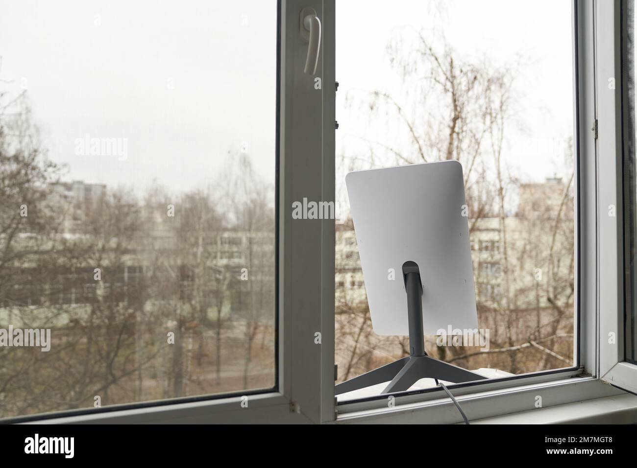 KIEW, UKRAINE - 8. JANUAR 2023: Starlink-Antenne für Satelliten-Internetzugang im Fenster des Hochhauses. Stockfoto