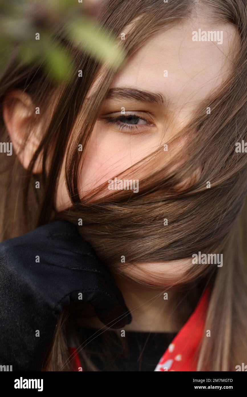Ein junges Mädchen bedeckt ihr Gesicht mit einem Haarstrauß Stockfoto