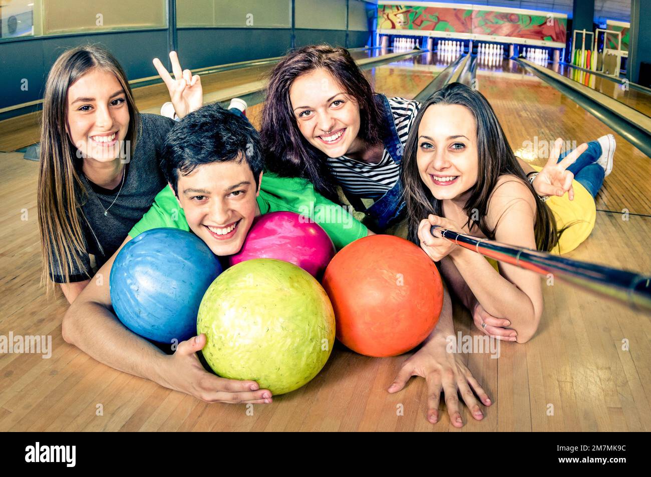 Beste Freunde, die Selfie-Stäbchen benutzen, um ein Foto auf der Bowlingbahn zu machen - Freundschaftskonzept mit jungen, verspielten Menschen, die Spaß miteinander haben - Weiche Konzentration auf den Kerl Stockfoto