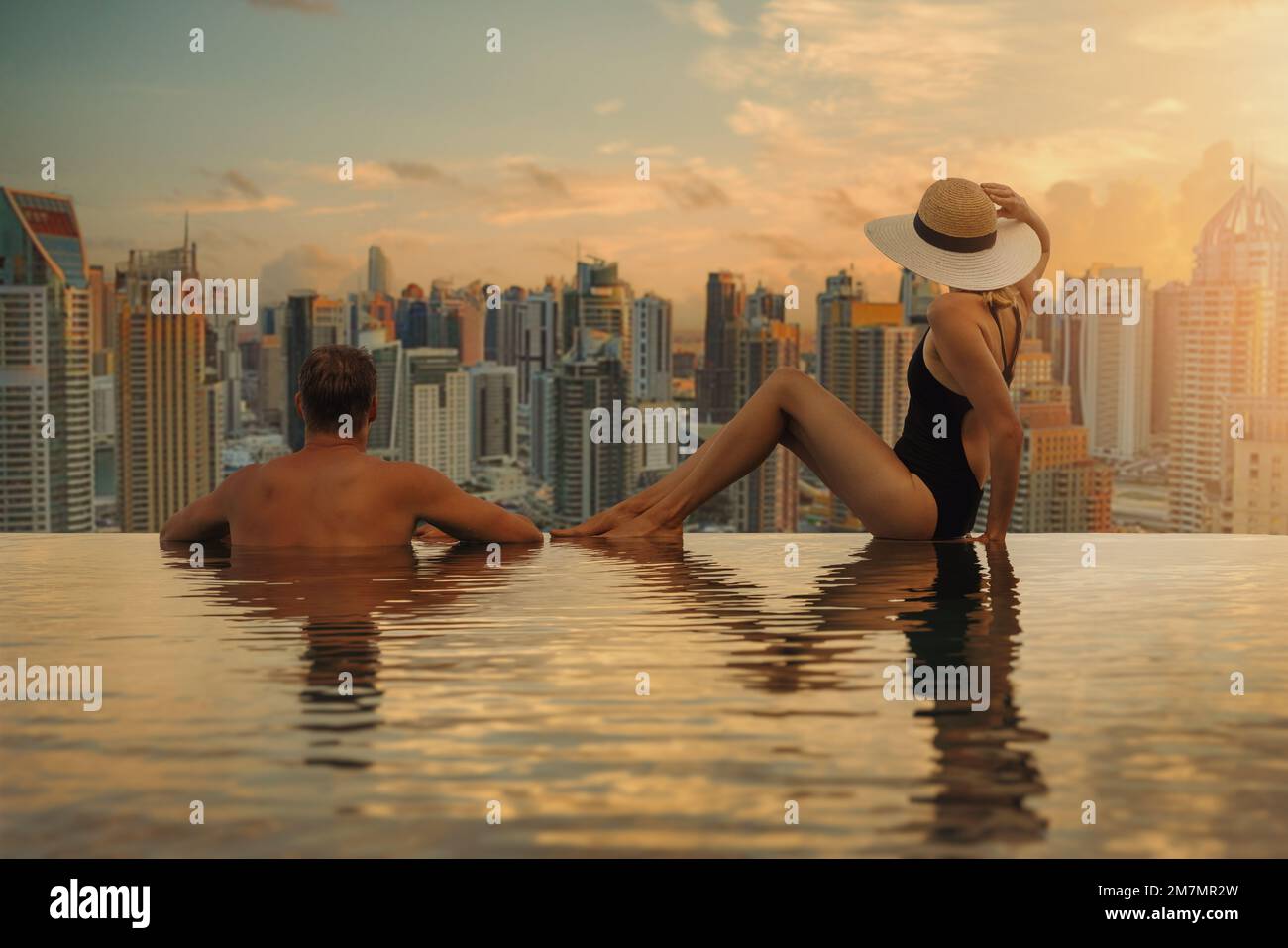 Ein Paar genießt die Skyline von Dubai mit Wolkenkratzer-Architektur vom Infinity Pool des Hotels bei Sonnenuntergang. Luxusurlaub und Reisen. Vereinigte Arabische Emirate Stockfoto