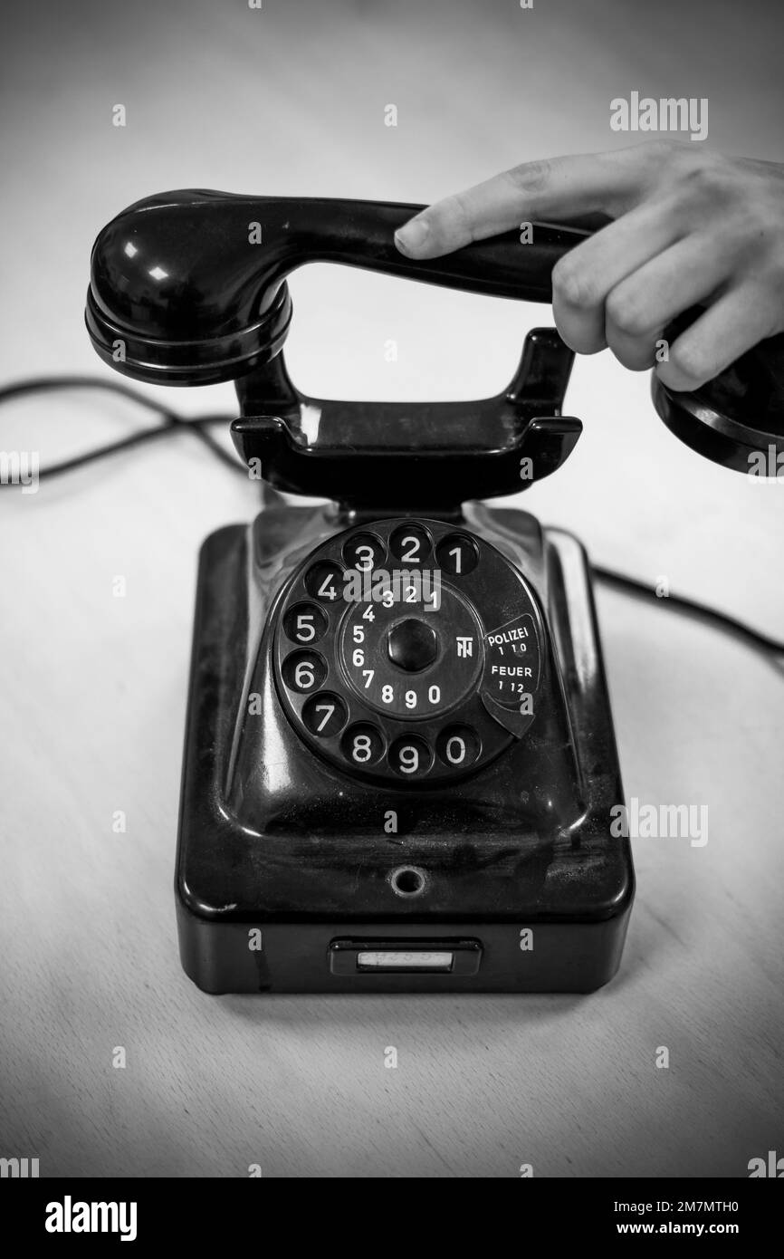 Weibliche Hand, die den Empfänger eines alten Telefons hält Stockfoto