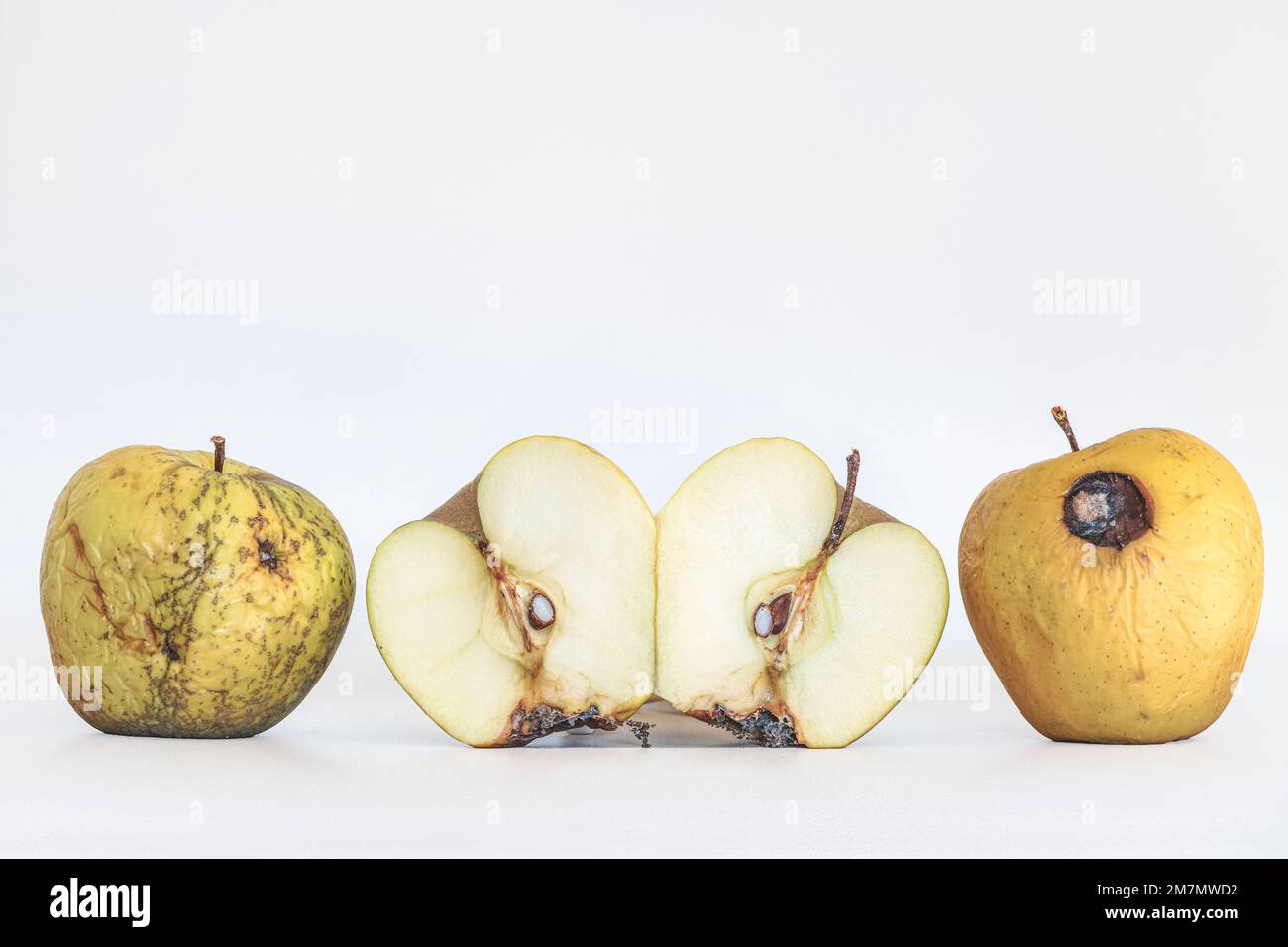 Verdorbene, dehydrierte und faule Äpfel, ein Apfel in zwei Hälften geschnitten, Früchte isoliert auf weißem Hintergrund Stockfoto
