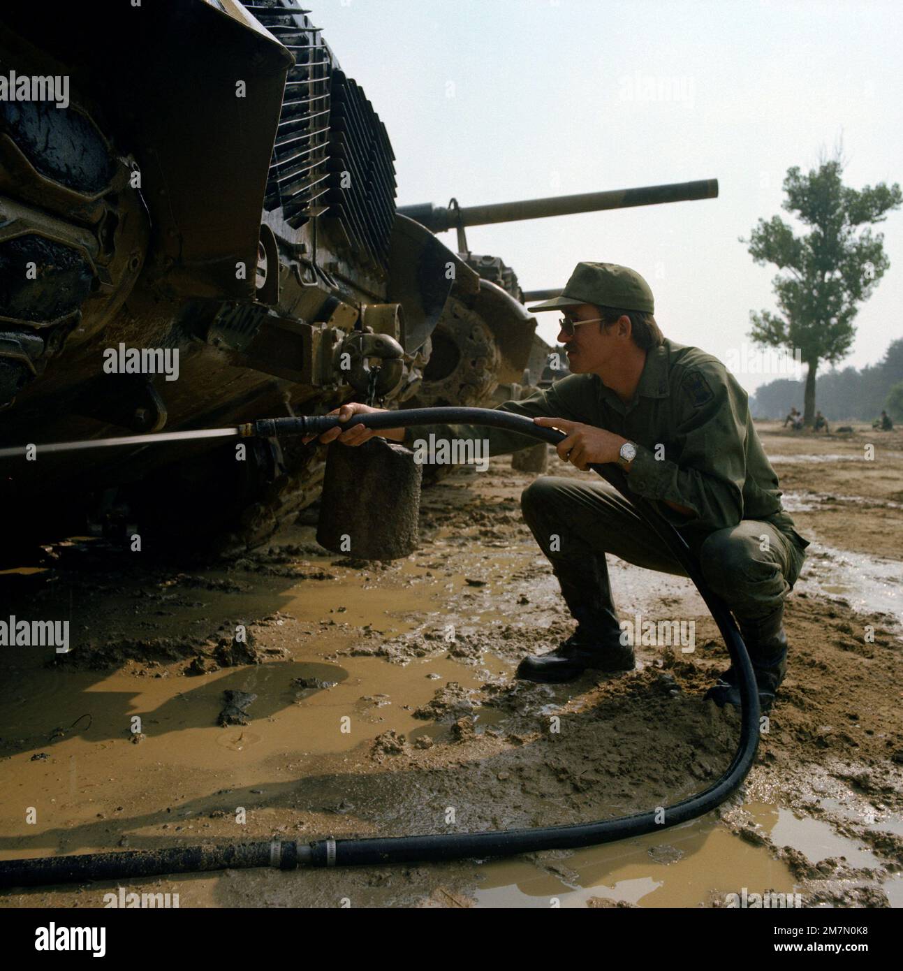 SPC 4 Daniel Kocher, Co A, 4. Milliarden, 73. Rüstung, benutzt einen Schlauch, um Schlamm von einem M-60-Tank während Reforger-Übungen am 7. Army Training Command zu waschen. Betreff Betrieb/Serie REFORGER Basis Grafenwohr Land Deutschland / Deutschland (DEU) Stockfoto