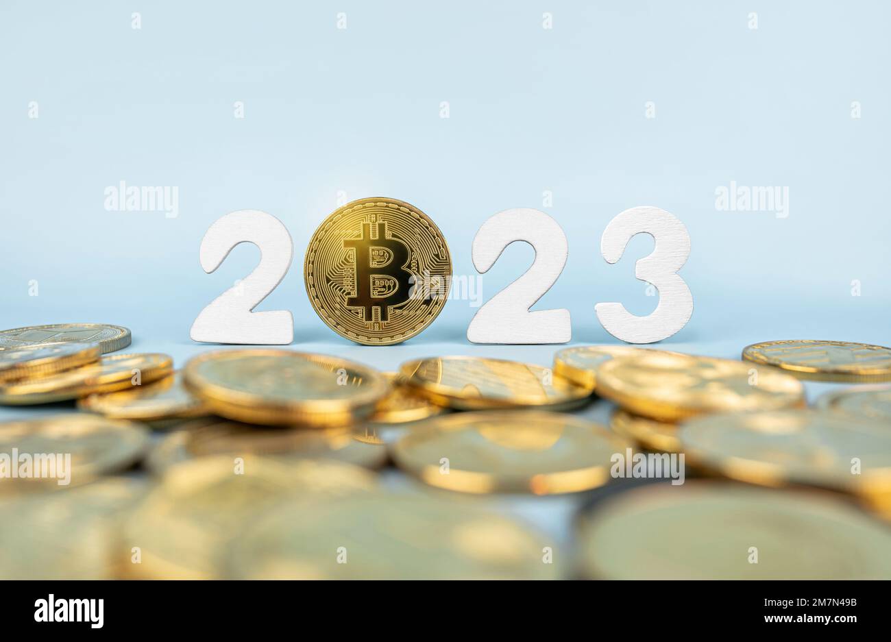 Bitcoin 2023-Preisprognose. BTC-Münze neben Kryptowährungs-Token und Jahreszahlen auf blauem Hintergrund. Nahaufnahme, Soft Focus. Stockfoto