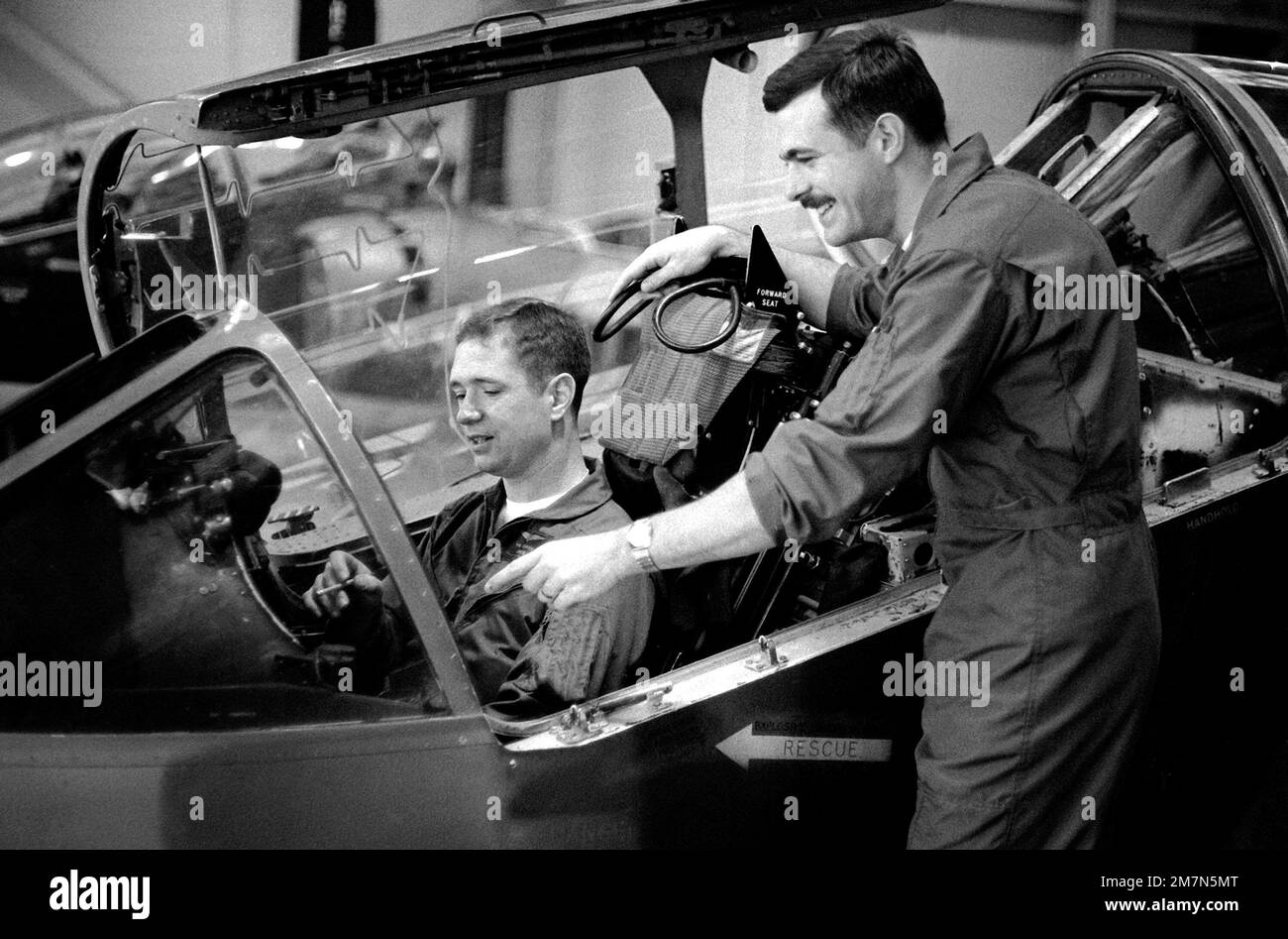 Während 1LT Van Hunter im Cockpit eines AV-8A Harrier-Flugzeugs sitzt, erklärt CPT Terry Cuny ihm einige der Instrumente. Die Männer und die Ausrüstung sind Teil des Marine Attack Squadron 203 (VMA-203). Basis: MCAS, Cherry Point Staat: North Carolina (NC) Land: Vereinigte Staaten von Amerika (USA) Stockfoto