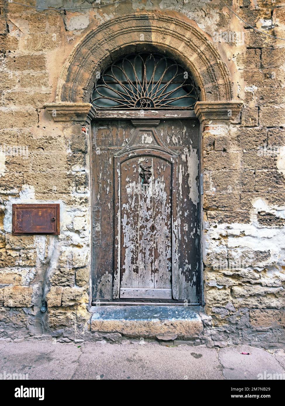 Urbaner Zerfall auf einem Steinhaus mit Torbogen und Holztür im Dorf Menfi, Sizilien Stockfoto