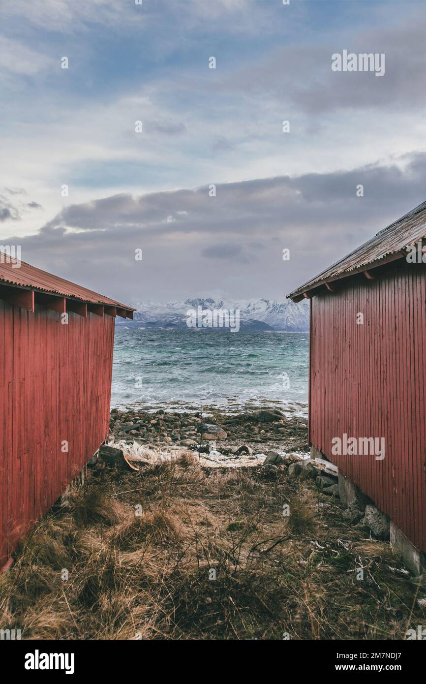 Zentrale Perspektive zwischen zwei traditionellen Rorbu-Hütten am Meer, Norwegen, typische Fjordlandschaft mit Bergen, Fischerhütte Stockfoto