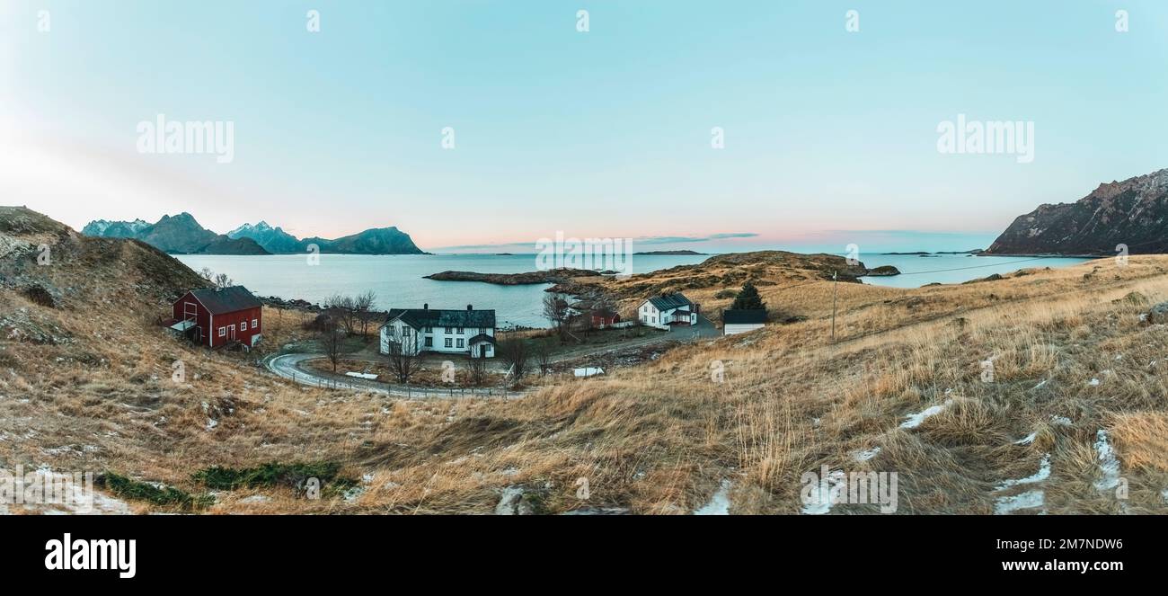 Abgelegenes Anwesen mit typisch nordischen Hütten und Häusern in abendlicher Atmosphäre, Fjordlandschaft mit kleinen Inseln, Abgeschiedenheit von der Außenwelt, Vesteralen, Norwegen, Panoramabild mit Horizont Stockfoto