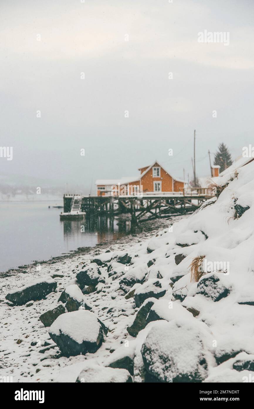 Gelbe Rorbu Häuser an der Küste, Fischerdorf in Vesteralen, Norwegen, Schneefall, Winter Stockfoto
