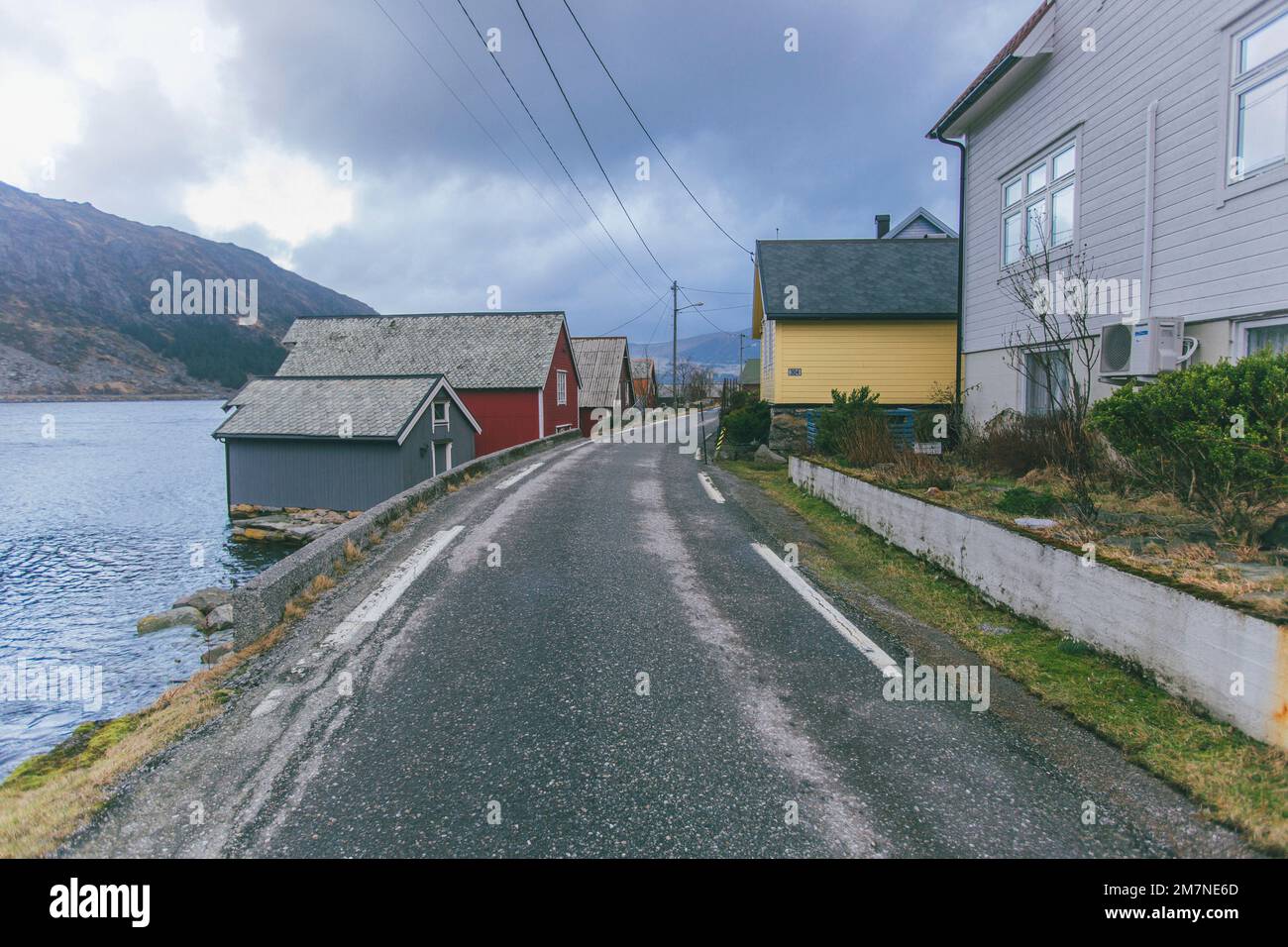 Einsame Fischerhütte an der Straße am Fjord in Norwegen, typische Fjordlandschaft mit kleinen Inseln, Abgeschiedenheit von der Außenwelt, Haus am See Stockfoto