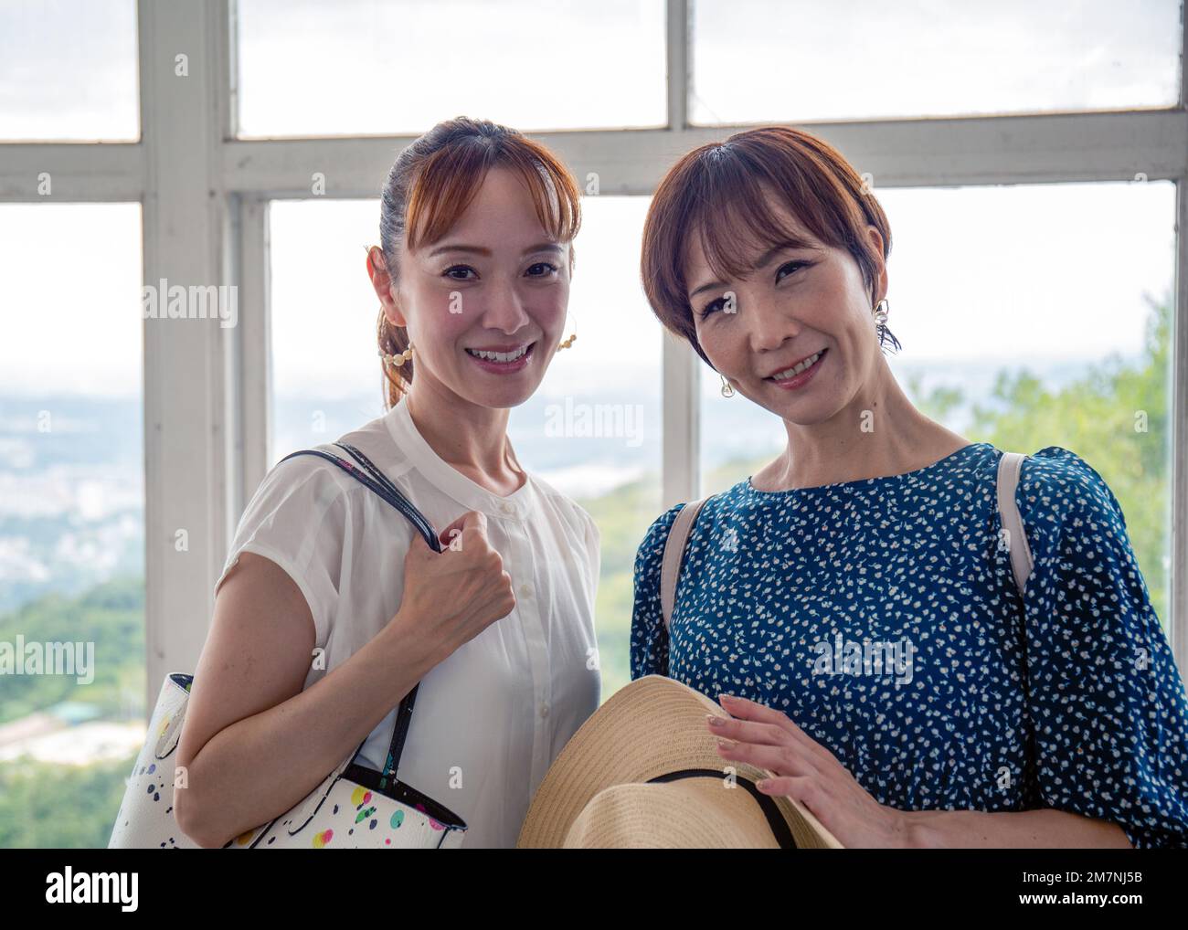 Zwei reife japanische Frauen, Freunde, Seite an Seite, an einem Tag, die in die Kamera schauen. Stockfoto